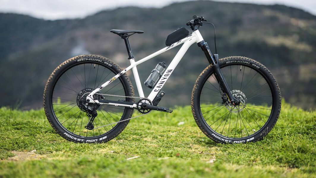 Canyon Grand Canyon AL 8 – Hardtail MTB for Versatile Trail Adventures Side view of the Canyon Grand Canyon AL 8 hardtail mountain bike set on a grassy hill, featuring front suspension, Schwalbe Rocket Ron tires, and a lightweight aluminum frame.