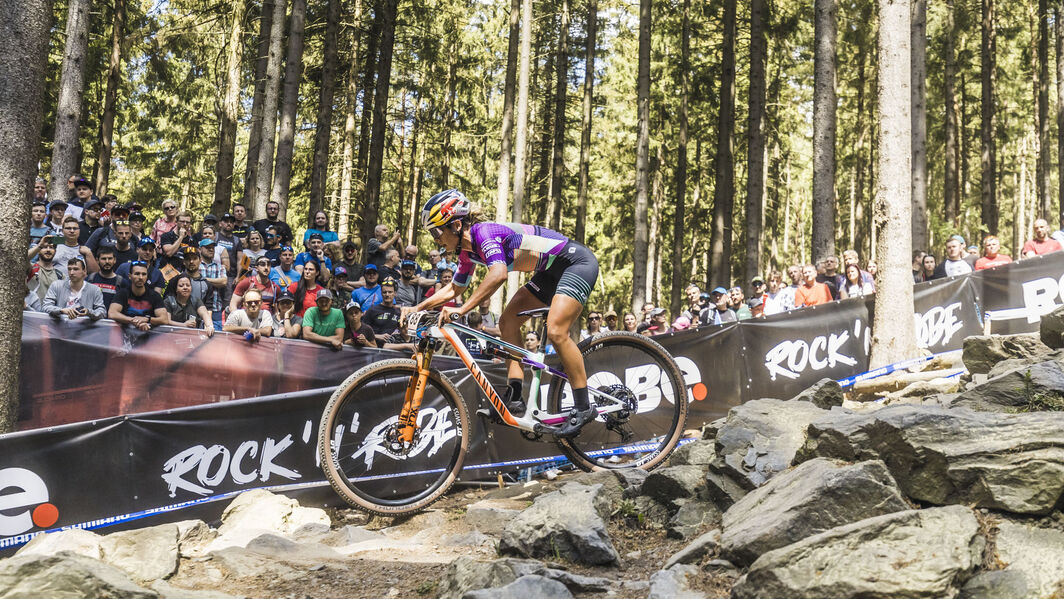 Canyon Lux Cross-Country MTB with 27.5 and 29 Inch Wheel Options Canyon Lux cross-country mountain bike racing through rocky terrain with crowd watching in the background, equipped with 27.5 or 29-inch wheels.