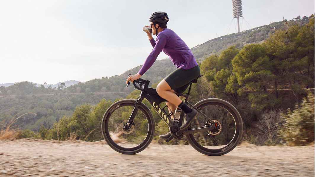 Canyon Grizl:ON electric gravel bike being ridden uphill, showcasing lightweight and durable frame material for optimal e-bike performance.