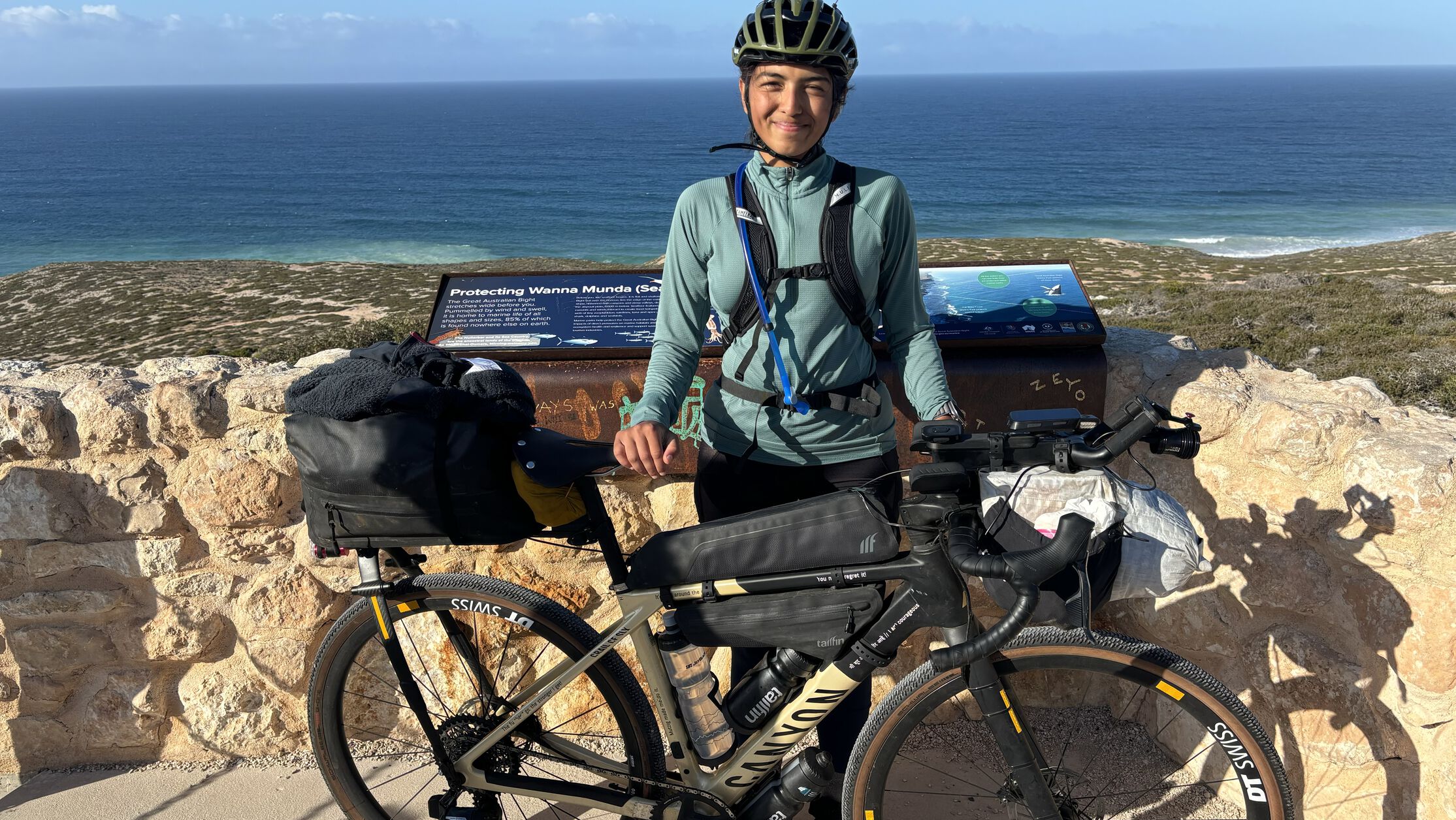 Vedangi Kulkarni standing with a fully equipped Canyon bike near a coastal viewpoint, illustrating essential bikepacking gear and setup for long-distance travel