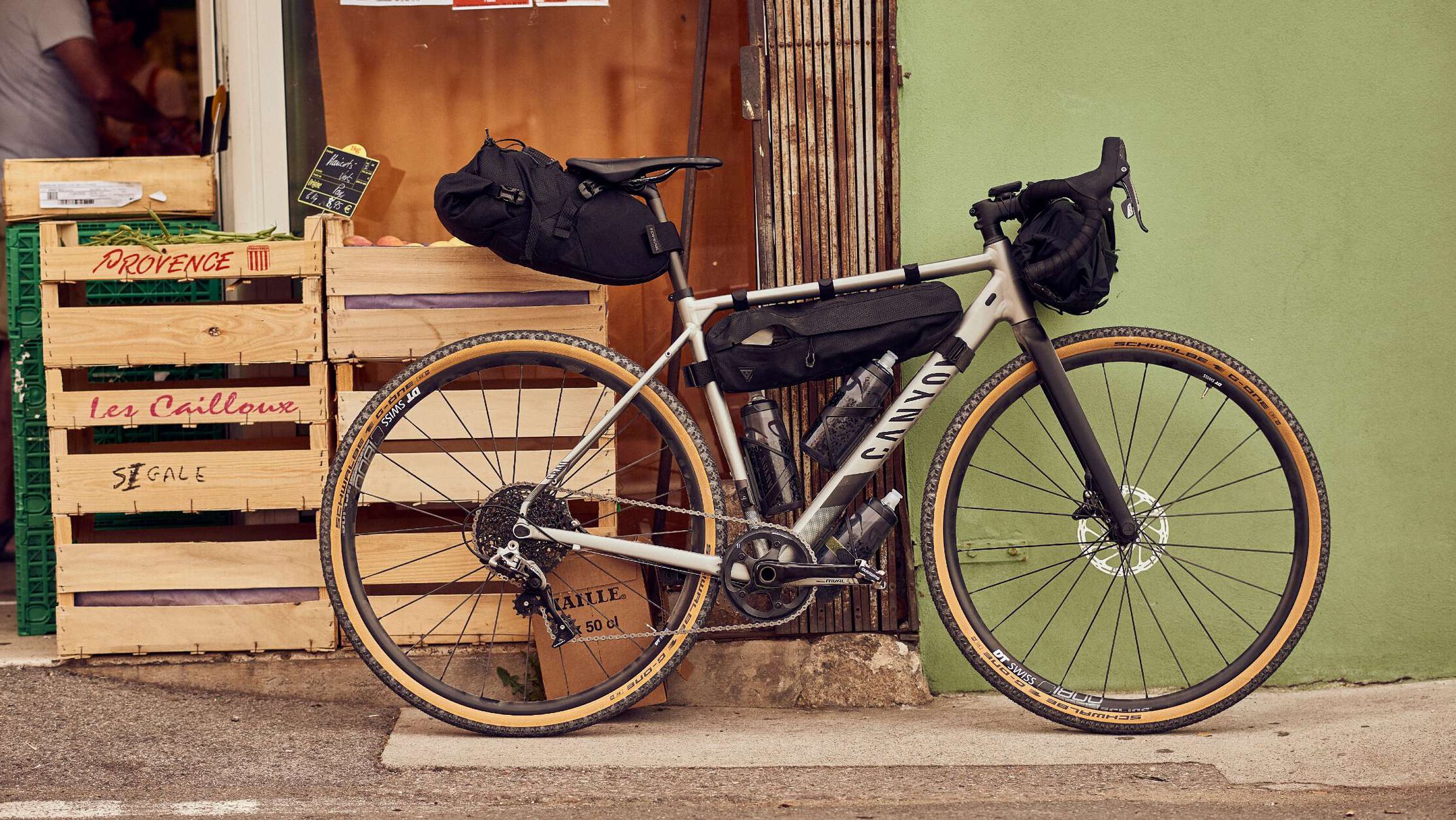 Canyon gravel bike fully equipped with bikepacking bags parked near a shop, showing ideal setup and gear essentials for beginner bikepackers